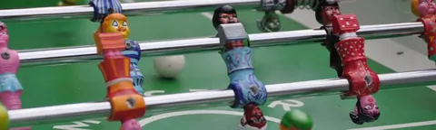 Close-up van de gekleurde poppetjes van een tafelvoetbalspel dat
                          buiten staat opgesteld.